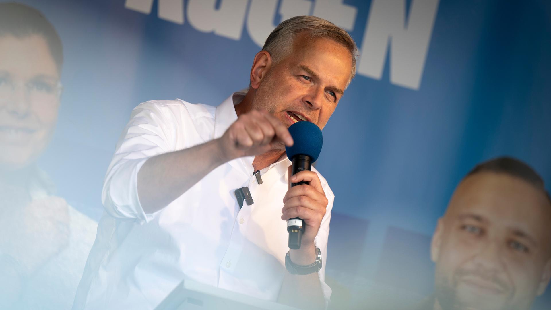 Der AfD-Politiker Leif-Erik Holm steht in Stralsund auf einer Bühne. Er hält ein blaues Mikrofon in der Hand und gestikuliert. Im Hintergrund ist ein blaues Parteibanner zu erkennen.
