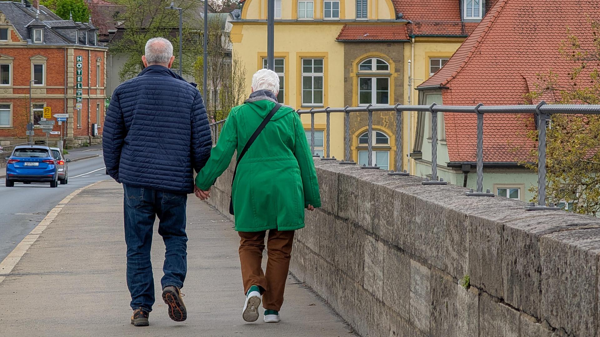 Ein Senioren-Paar spaziert über eine Brücke in Kitzingen, Bayern