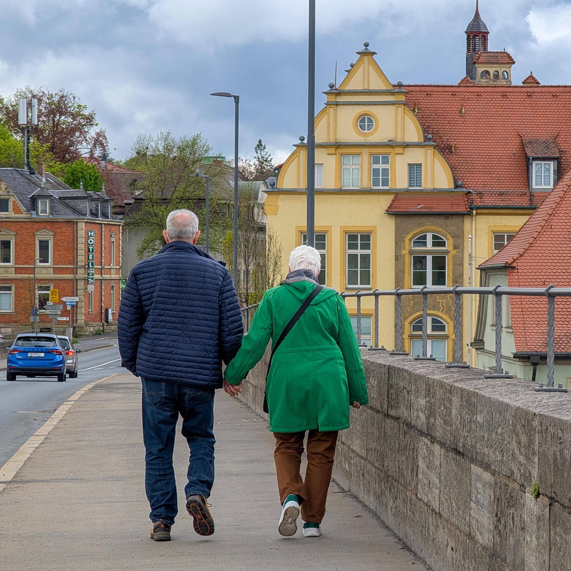 Ein Senioren-Paar spaziert über eine Brücke in Kitzingen, Bayern