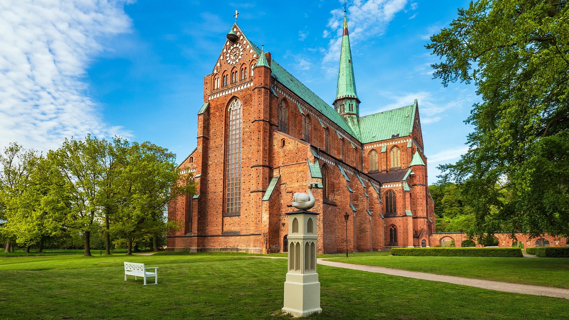 Ein hochgotischer Backsteinbau mit grünem Dach.