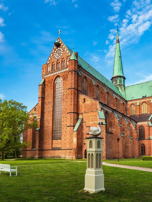 Ein hochgotischer Backsteinbau mit grünem Dach.