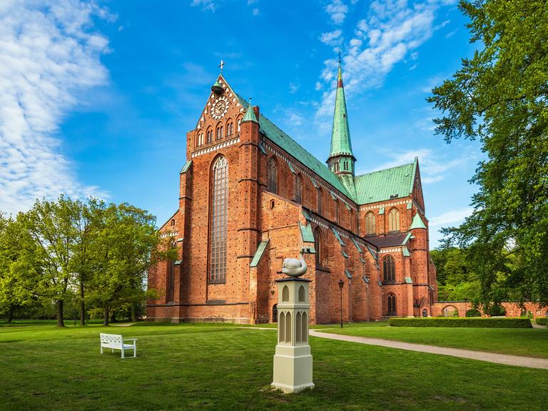 Ein hochgotischer Backsteinbau mit grünem Dach.