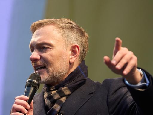 Der FDP-Vorsitzende Christian Lindner spricht bei einem Wahlkampfauftritt. Er trägt einen schwarzen Mantel und hält ein Mikrophon in der Hand.