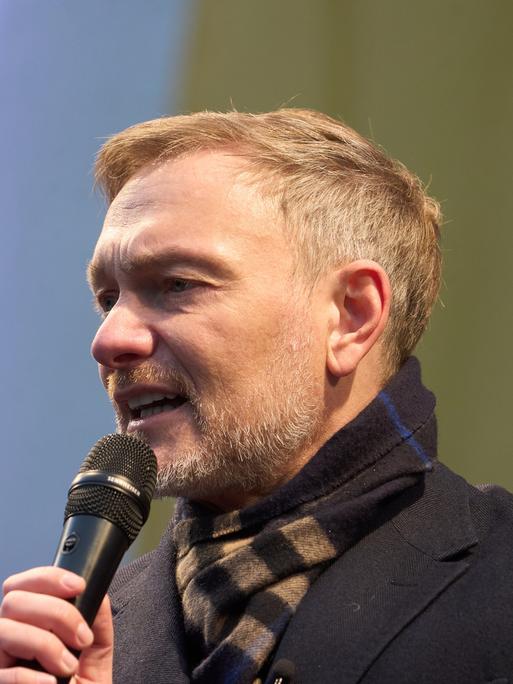 Der FDP-Vorsitzende Christian Lindner spricht bei einem Wahlkampfauftritt. Er trägt einen schwarzen Mantel und hält ein Mikrophon in der Hand.