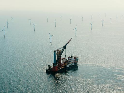 Luftaufnahme eines Installationsschiffes beim Bau eines Windrads in einem Offshore-Windpark.