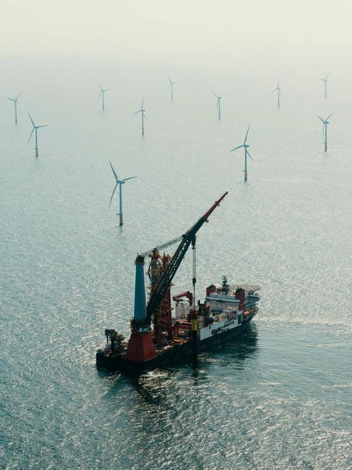 Luftaufnahme eines Installationsschiffes beim Bau eines Windrads in einem Offshore-Windpark.