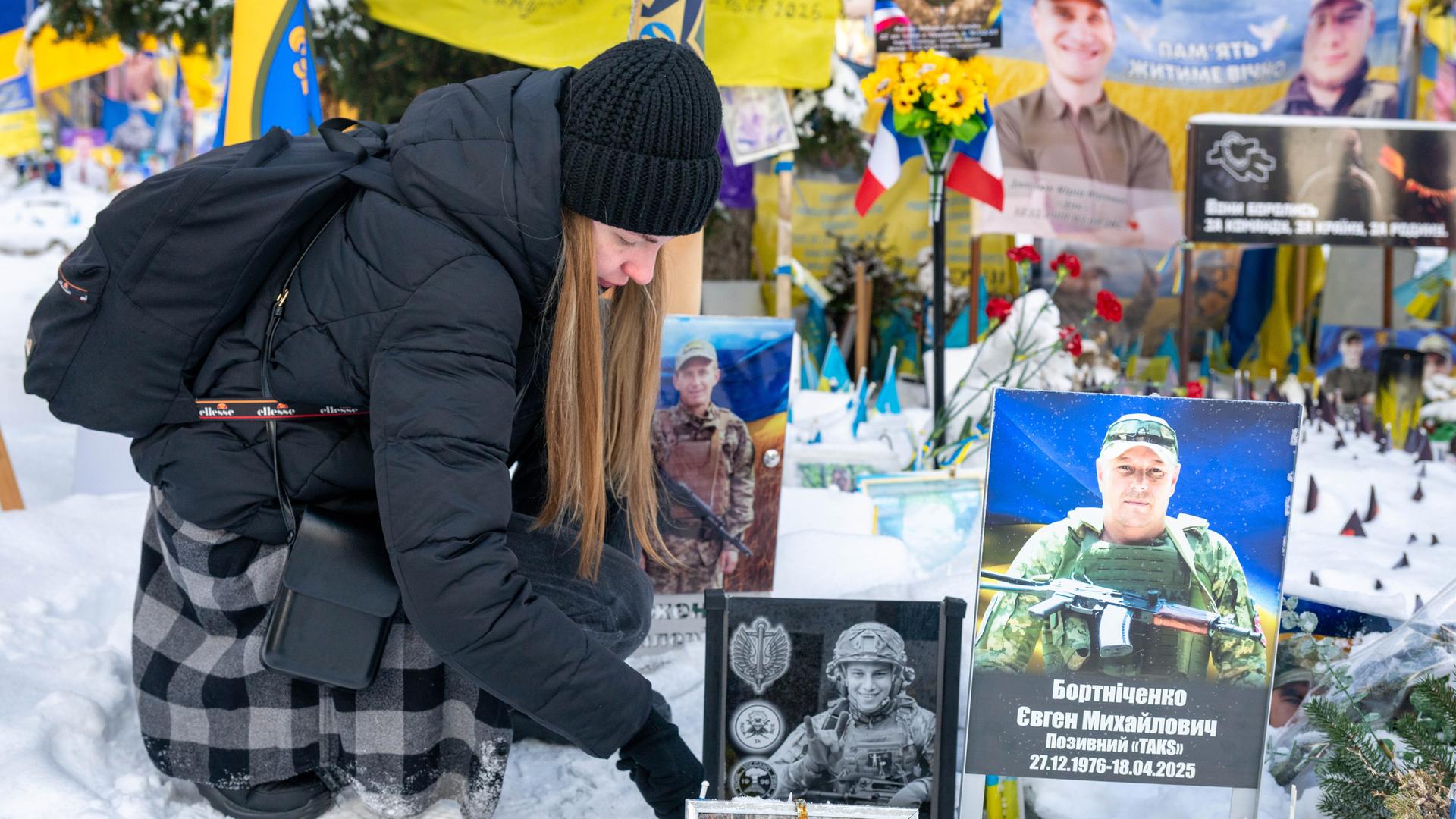 Eine Ukrainierin wischt Schnee von dem Foto ihres an der Front gestorbenen Mannes auf dem Maidan-Platz in Kiew