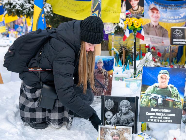 Eine Ukrainierin wischt Schnee von dem Foto ihres an der Front gestorbenen Mannes auf dem Maidan-Platz in Kiew.