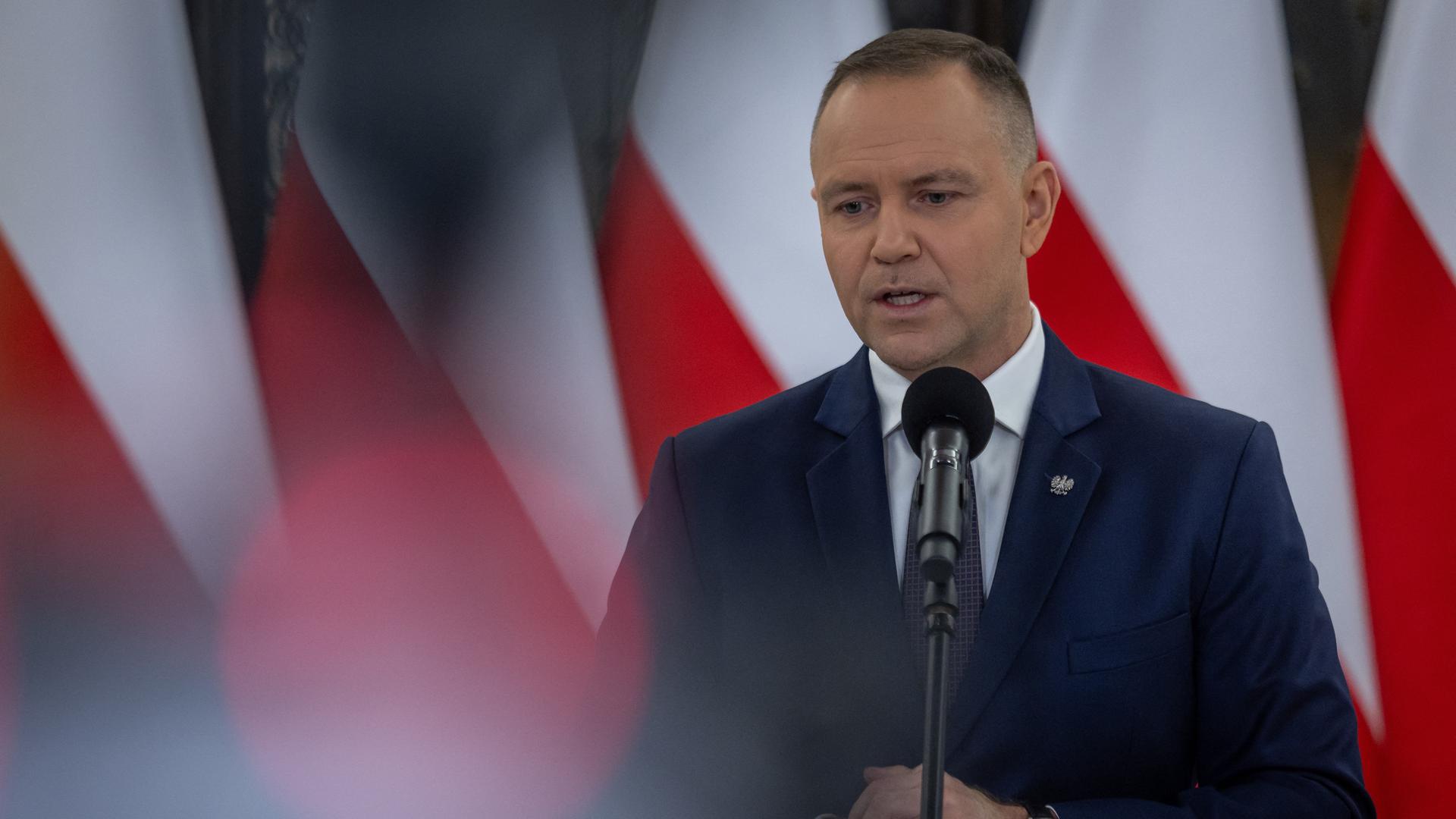 Der polnische Präsident Karol Nawrocki bei einer Pressekonferenz. Im Hintergrund sind Landesflaggen zu sehen.