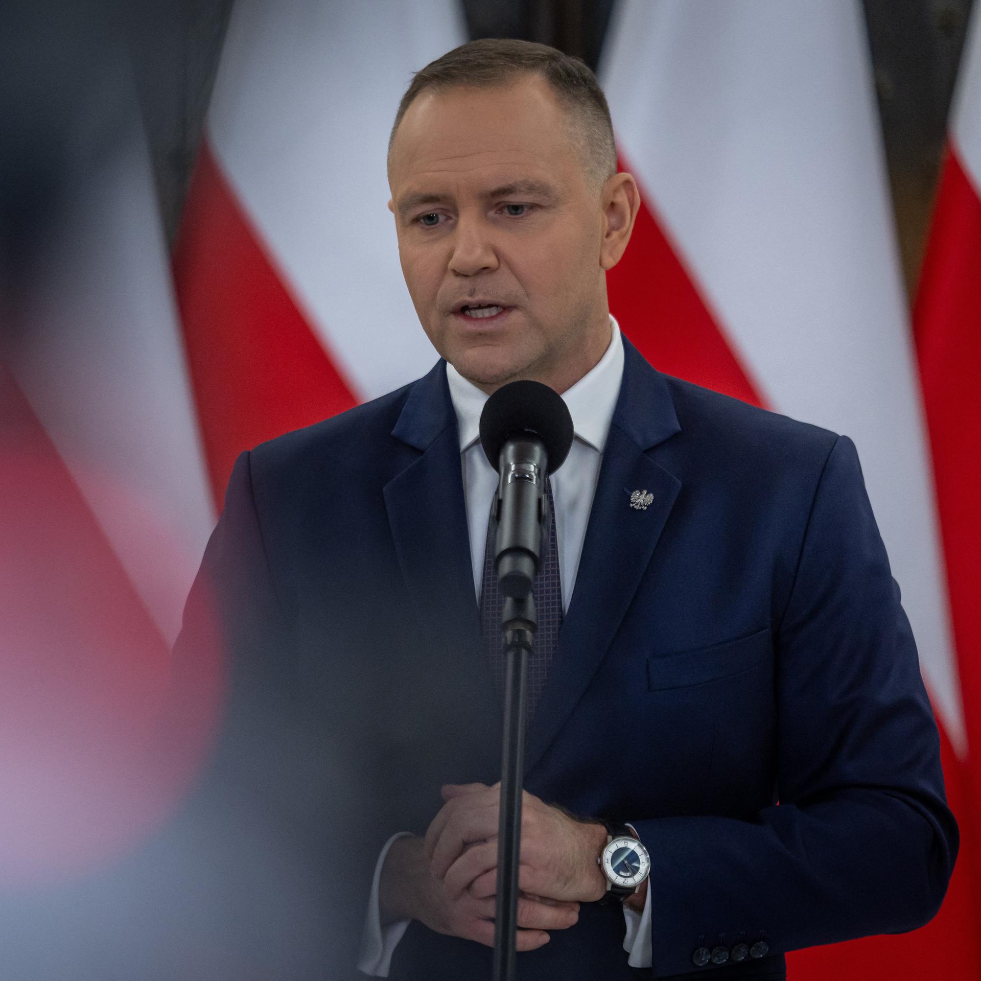 Der polnische Präsident Karol Nawrocki bei einer Pressekonferenz. Im Hintergrund sind Landesflaggen zu sehen.