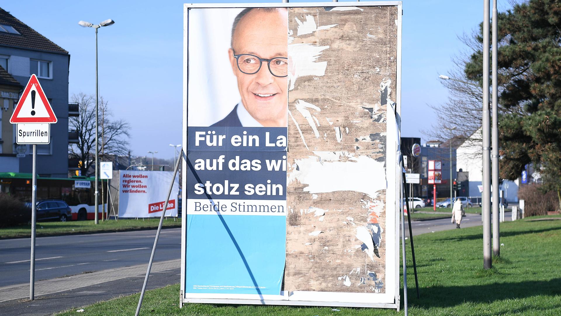 Ein beschädigtes und in Teilen zerstörtes Wahlplakat der CDU. Friedrich Merz mit der Aufschrift: Für ein Land, auf das wir wieder stolz sein können. 