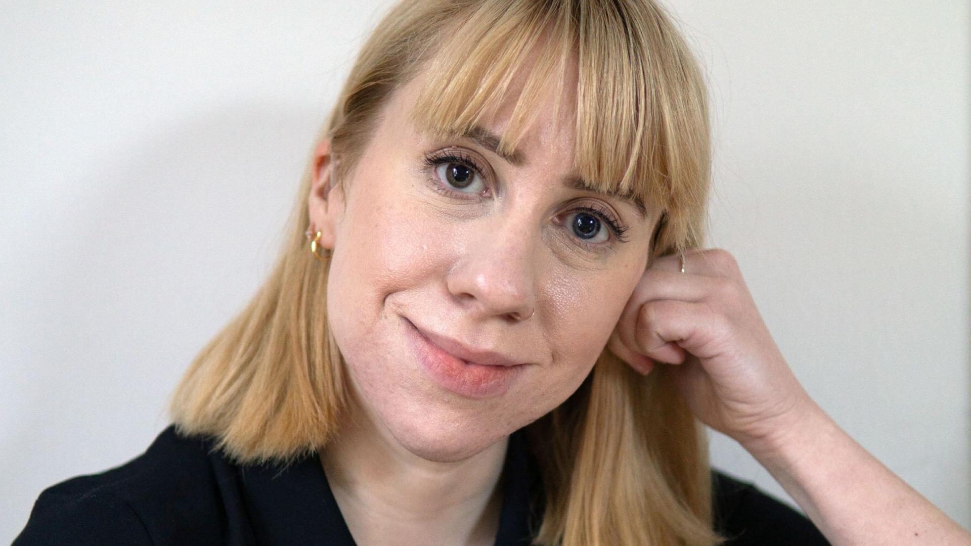 Die Autorin Katrin Aimee schaut mit einem stillen Lächeln direkt in die Kamera.