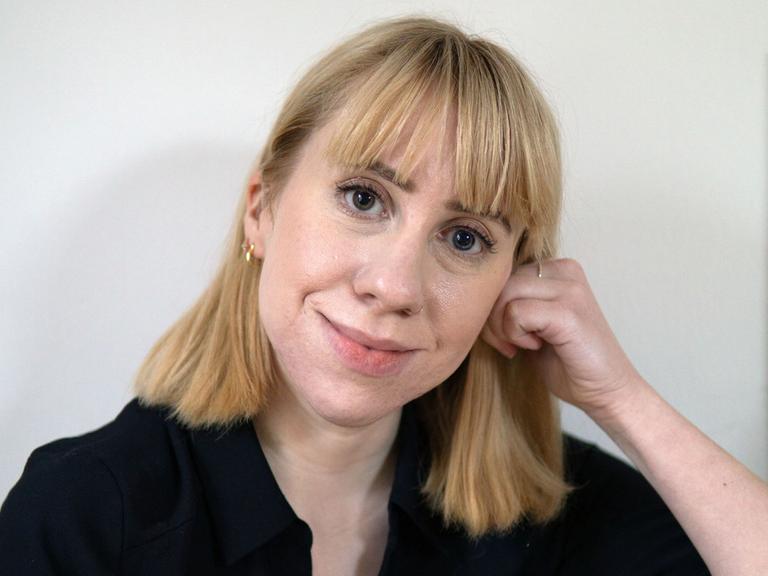 Die Autorin Katrin Aimee schaut mit einem stillen Lächeln direkt in die Kamera.