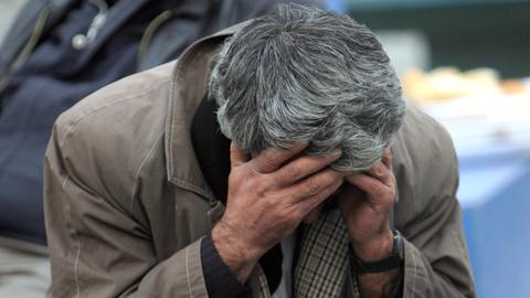 Archivbild: Ein Mann sitzt am Rande eines nach einem Erdbeben eingestürzten Gebäudes in der Provinz Van.