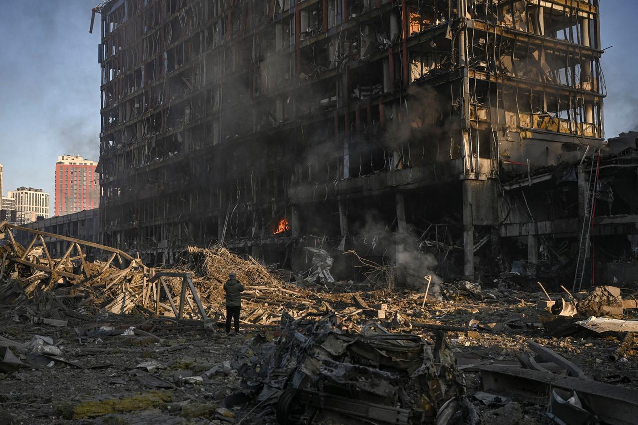 Ein Mann steht vor dem bei einem Angriff zerstörten Einkaufszentrum in Kiew in der Ukraine.
