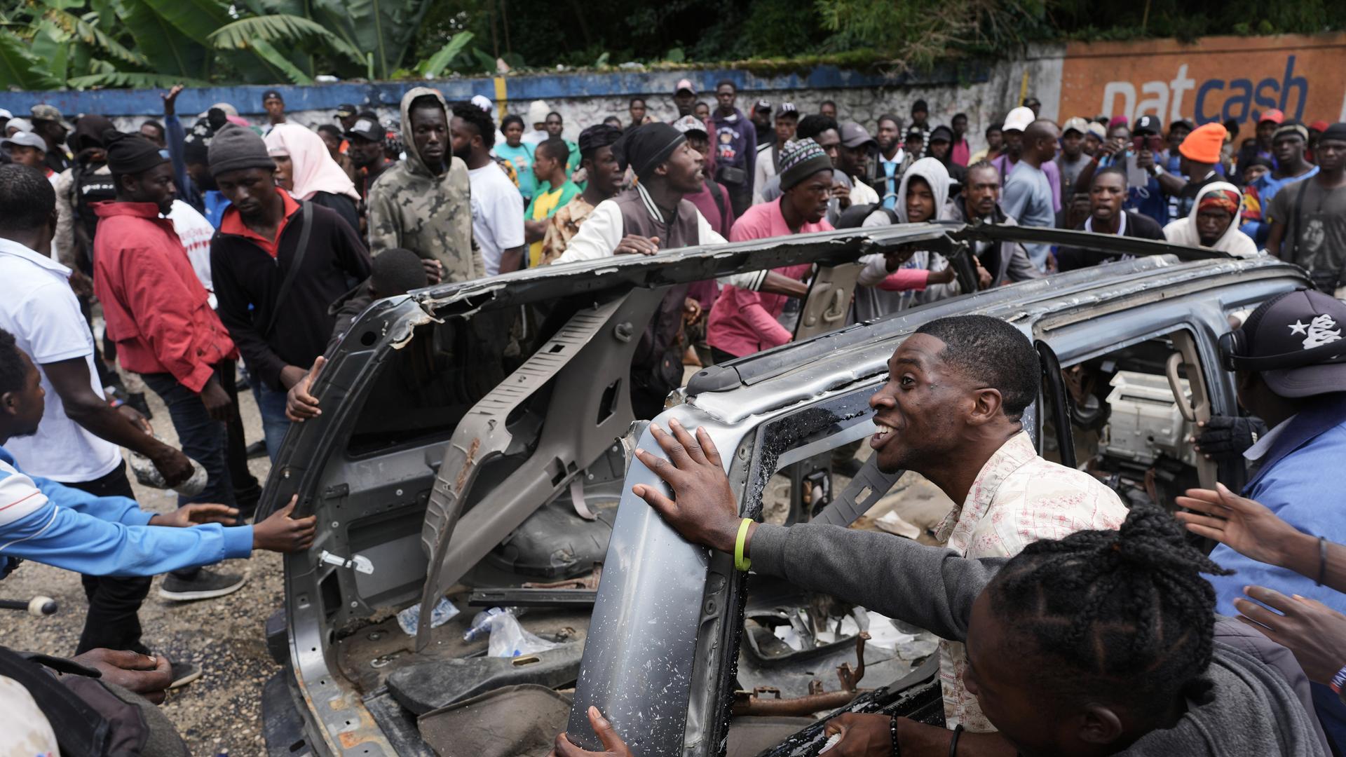 Haiti, Port-au-Prince: Anwohner versuchen, ein Auto umzukippen, um eine Straße zu blockieren, während sie nach tödlichen Bandenangriffen im Stadtteil Kenscoff für ein Eingreifen der Polizei demonstrieren. Haiti, Port-au-Prince: Anwohner versuchen, ein Auto umzukippen, um eine Straße zu blockieren, während sie nach tödlichen Bandenangriffen im Stadtteil Kenscoff für ein Eingreifen der Polizei demonstrieren.