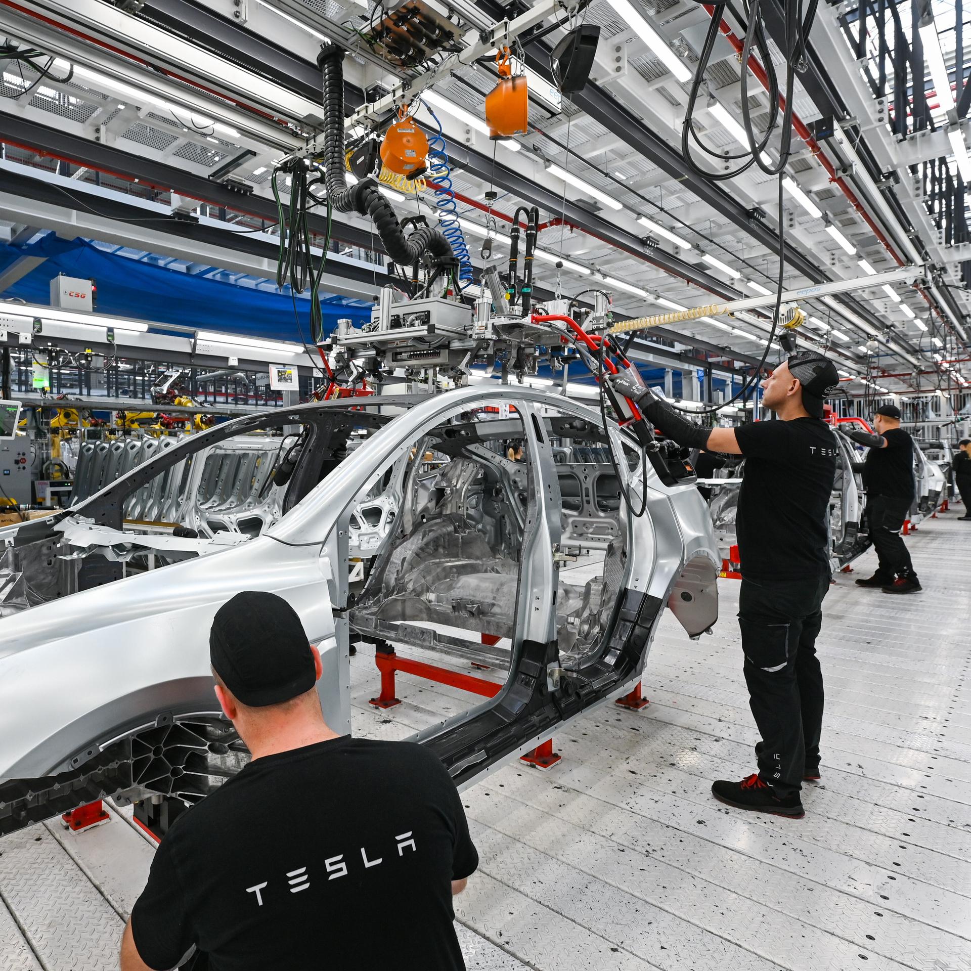 Arbeiter montieren in der Produktionshalle der Tesla-Gigafactory in Grünheide (Brandenburg) ein Elektrofahrzeug vom Typ Tesla Model Y.