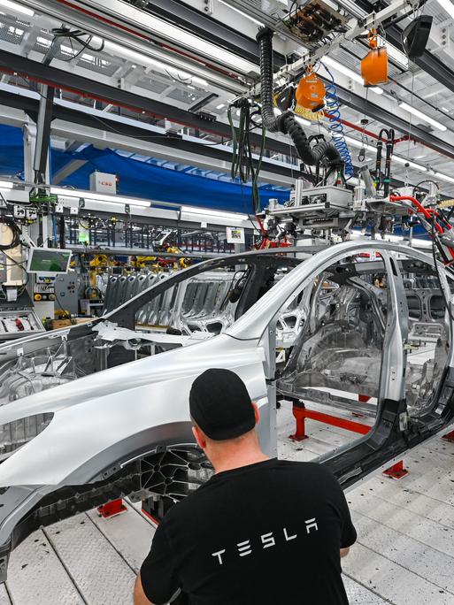 Arbeiter montieren in der Produktionshalle der Tesla-Gigafactory in Grünheide (Brandenburg) ein Elektrofahrzeug vom Typ Tesla Model Y.