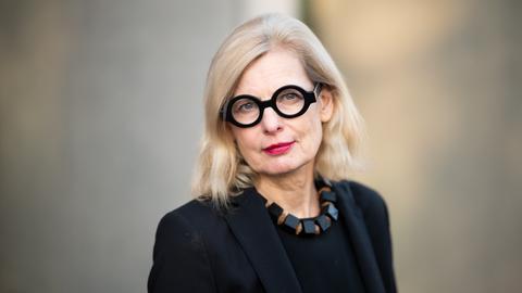 Claudia Guderian trägt eine schwarz umrandete Brille, eine schwarze Kette und ein schwarzes Oberteil. Sie schaut freundlich und direkt in die Kamera.