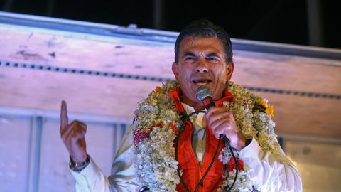 Rodrigo Paz, Boliviens Präsidentschaftskandidat der Christlich-Demokratischen Partei (PDC), hält nach der Stichwahl zur Präsidentschaftswahl eine Rede. Er trägt Blumenschmuck um den Hals und hält den Zeigefinger in die Höhe (La Paz, Bolivien, 19.10.2025)