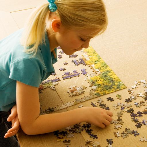 Ein Mädchen sitzt auf dem Boden und puzzelt