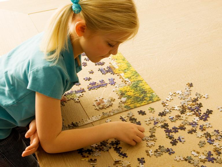 Ein Mädchen sitzt auf dem Boden und puzzelt