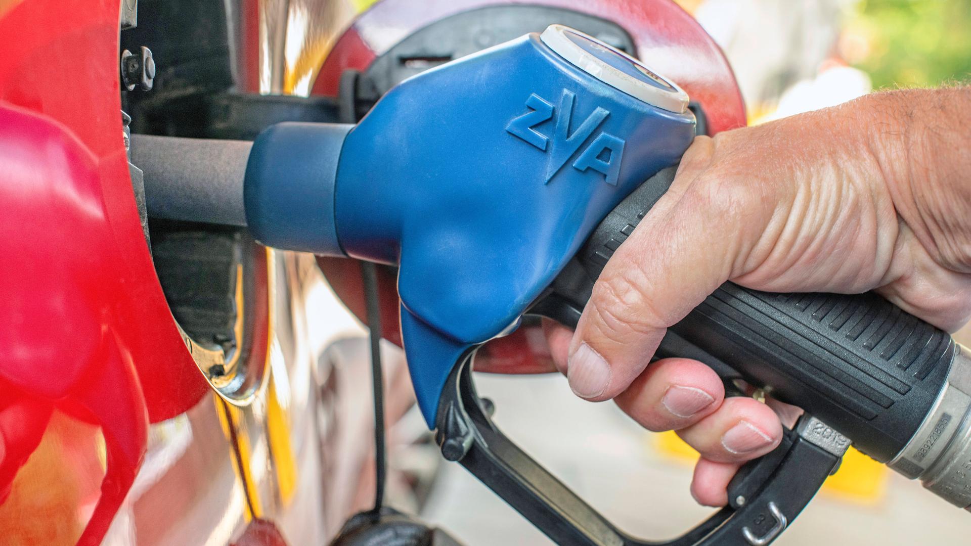 Ein Kunde tankt an einer Tankstelle in München mit einer Hand an der Zapfpistole E5 Ein Kunde tankt an einer Tankstelle in München mit einer Hand an der Zapfpistole E5