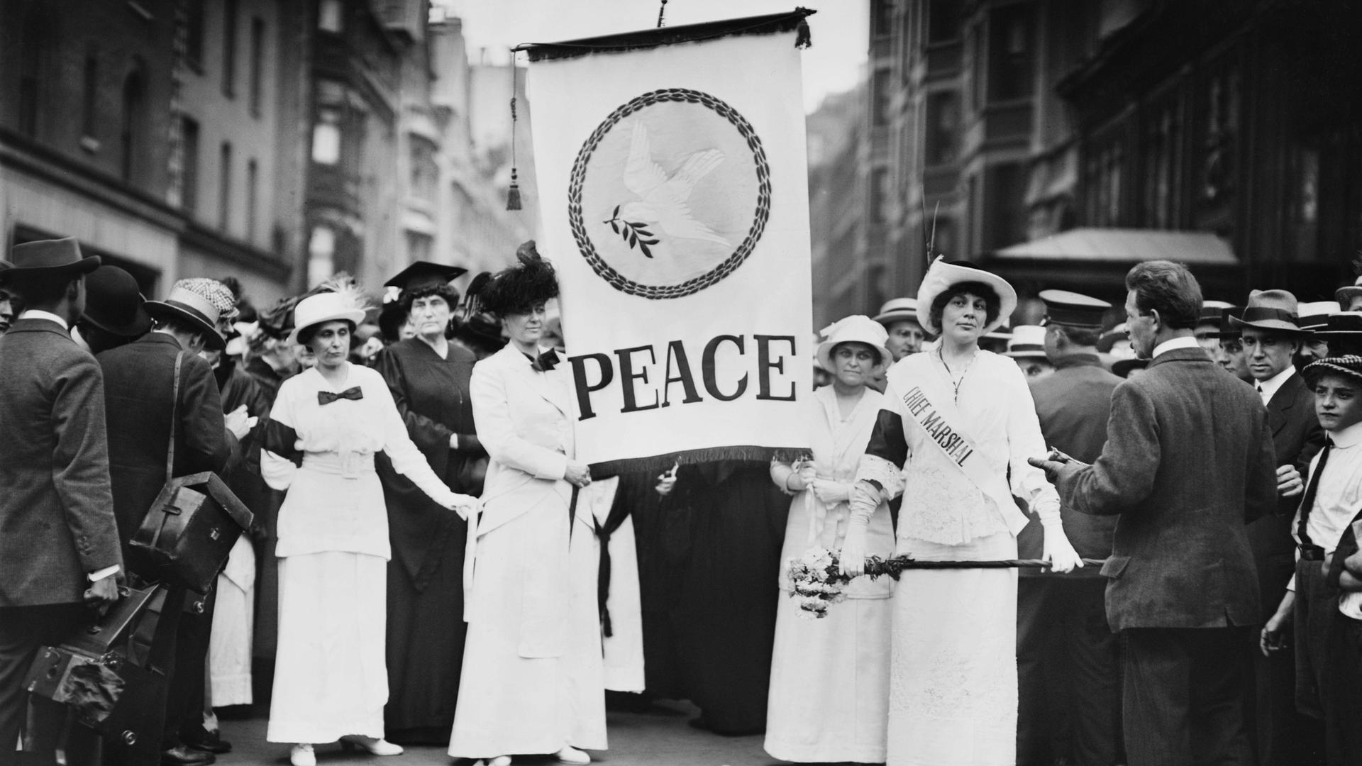 Friedensaktivistinnen protestieren Ende August 1914 in New York gegen den Ersten Weltkrieg. Frauen halten ein Banner mit der Aufschrift „Peace“ – „Frieden“ in der Hand. 