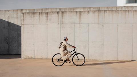 Eine Frau fährt mit einem Fahrrad an einer Wand vorbei 