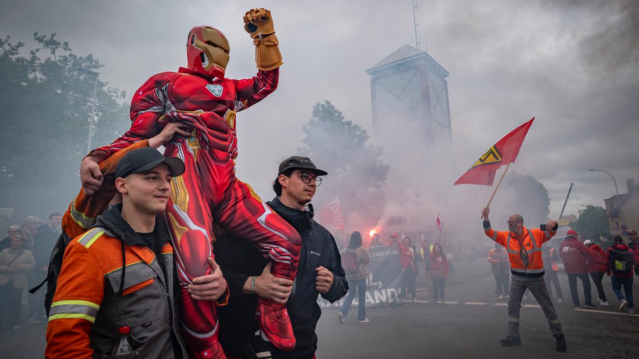 Demonstranten tragen einen als Comicheld Iron Man verkleideten Kollegen auf den Schultern. Seine Faust ist gereckt. Demonstranten tragen einen als Comicheld Iron Man verkleideten Kollegen auf den Schultern. Seine Faust ist gereckt.