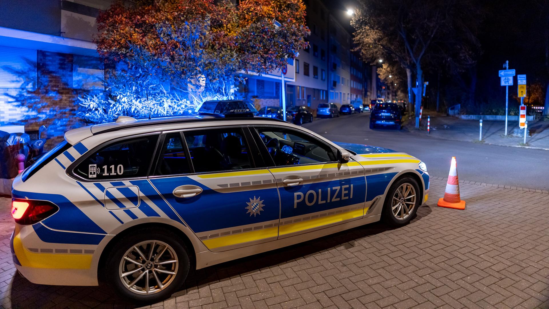 Es ist dunkel. Ein Polizeiwagen steht mit Blaulicht auf einer Straße in einem Wohnviertel. Es ist dunkel. Ein Polizeiwagen steht mit Blaulicht auf einer Straße in einem Wohnviertel.