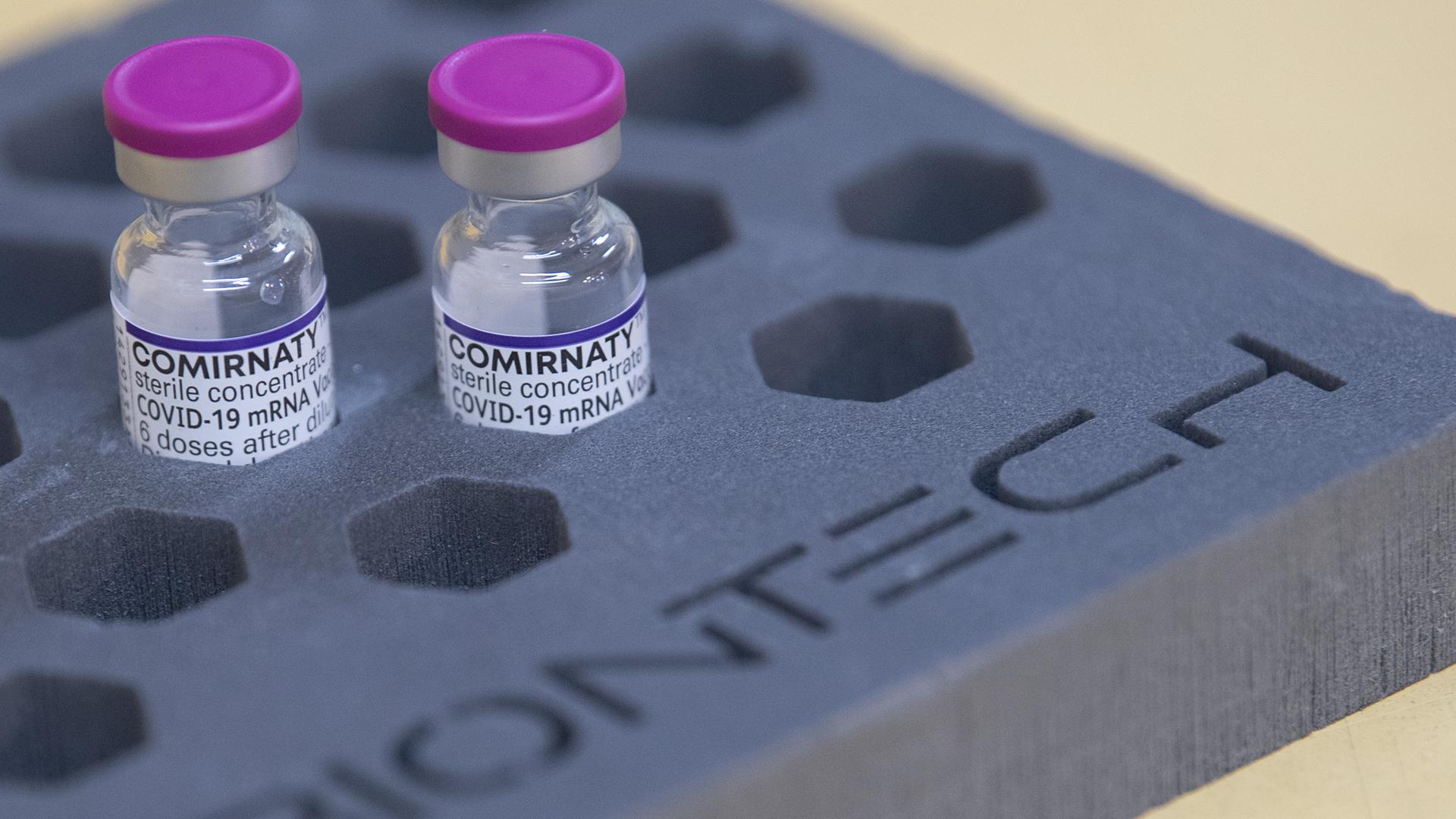 Fläschen des Biontech-Impfstoffs Comirnaty gegen das Corona-Virus stehen stehen in einer Schaumverpackung mit Biontech-Schriftzug auf einem Tisch.
