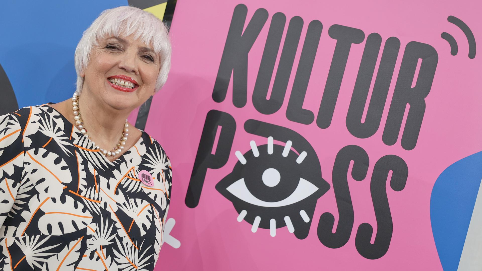 Kulturstaatsministerin Claudia Roth (Bündnis90/Die Grünen) steht vor dem Logo des "KulturPass".