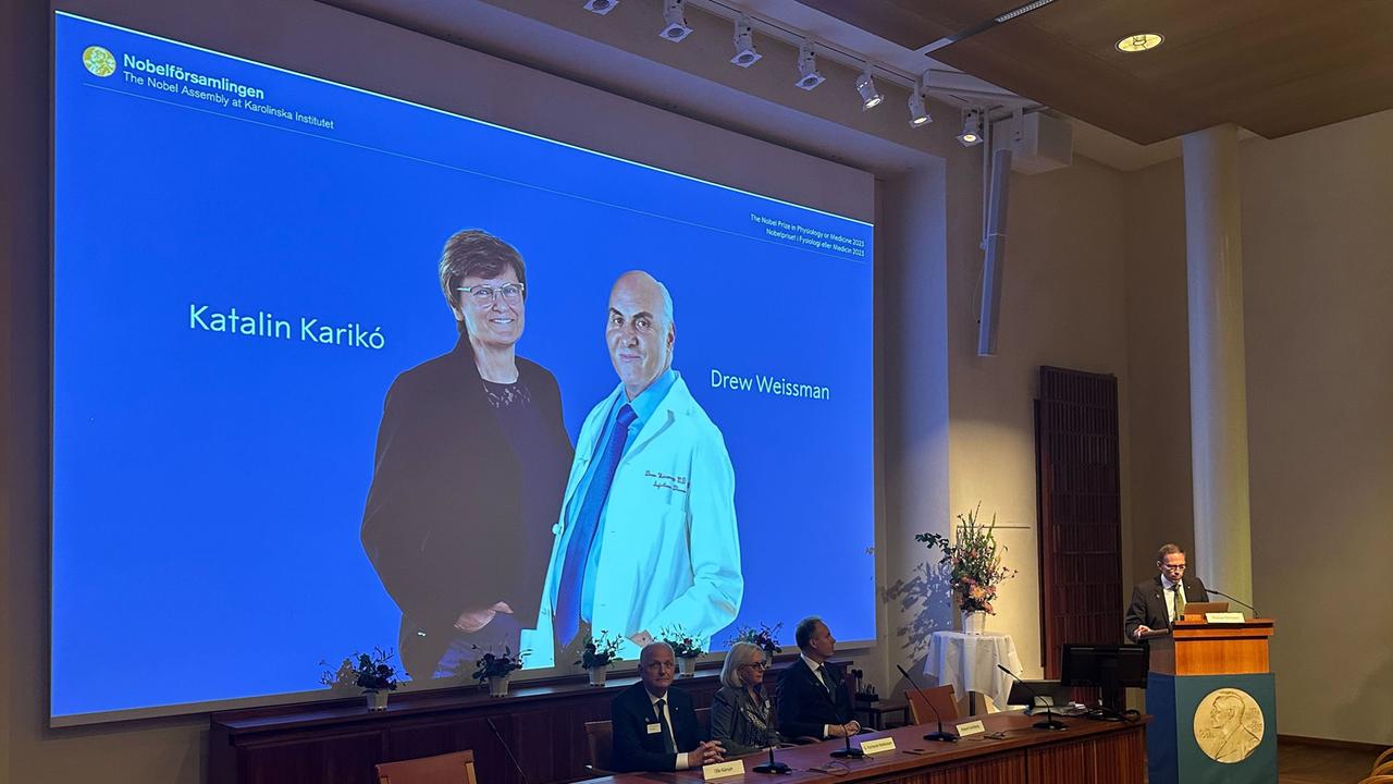 Schweden, Stockholm: Fotos der Wissenschaftlerin Katalin Kariko und des Wissenschaftlers Drew Weissman sind bei der Bekanntgabe des Nobelpreises für Medizin auf einer Leinwand zu sehen.