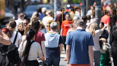 Unscharfes Bild einer Menschenmenge in einer Fußgängerzone. Über manche Gesichter wurden grafische Symbole von Aktenordnern gelegt.