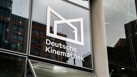 Blick auf eine Glasfassade mit dem Logo und dem Schriftzug der Deutschen Kinemathek. Blick auf eine Glasfassade mit dem Logo und dem Schriftzug der Deutschen Kinemathek.