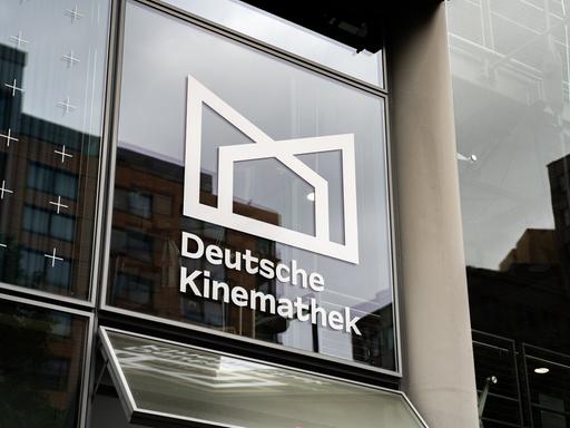 Blick auf eine Glasfassade mit dem Logo und dem Schriftzug der Deutschen Kinemathek.