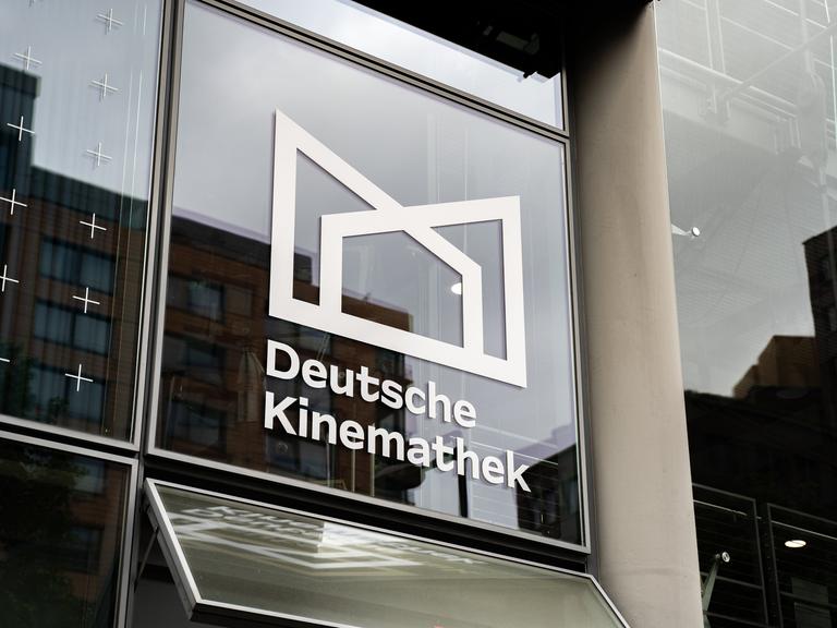 Blick auf eine Glasfassade mit dem Logo und dem Schriftzug der Deutschen Kinemathek.