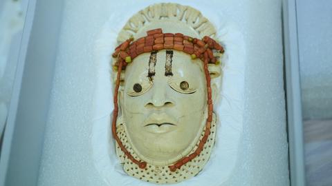 Eine Miniaturmaske aus Elfenbein in einer Vitrine.