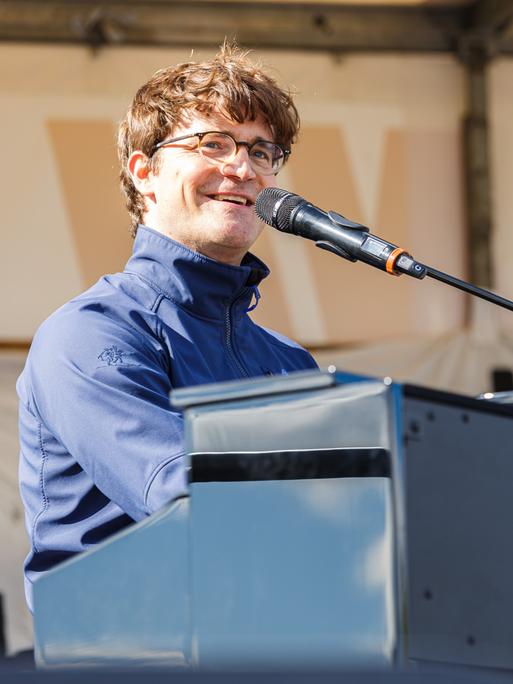 Bodo Wartke sitzt auf einer Bühne am Keyboard und singt