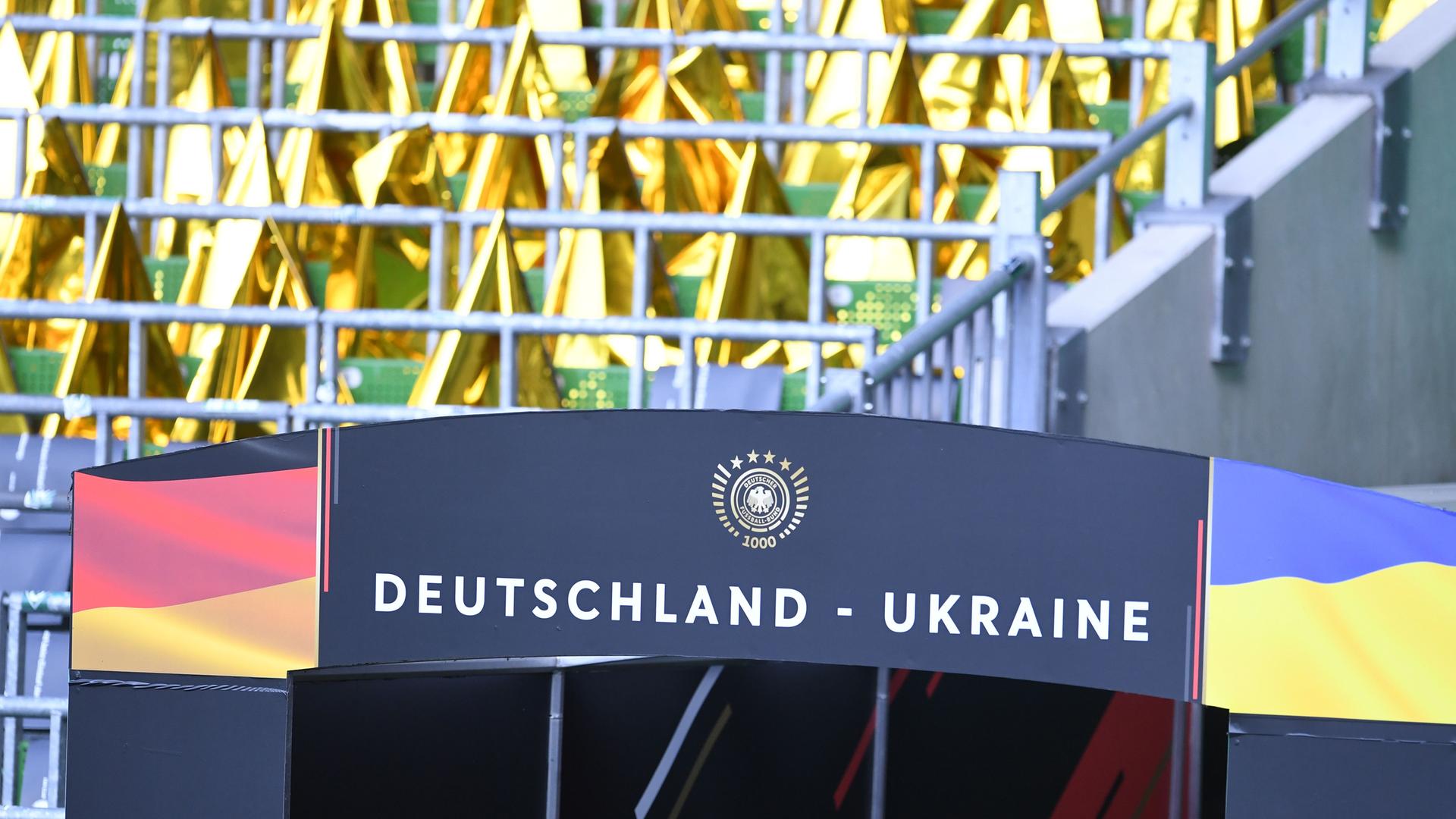 Das BIld zeigt über dem Eingang des Spielertunnels die beiden Flaggen der Länder, ein Logo des Deutschen Fußballbundes mit dem Hinweis auf das 1.000. Spiel und den Schriftzug "Deutschland - Ukraine". Dahinter unscharf eine Tribüne. Das BIld zeigt über dem Eingang des Spielertunnels die beiden Flaggen der Länder, ein Logo des Deutschen Fußballbundes mit dem Hinweis auf das 1.000. Spiel und den Schriftzug "Deutschland - Ukraine". Dahinter unscharf eine Tribüne.