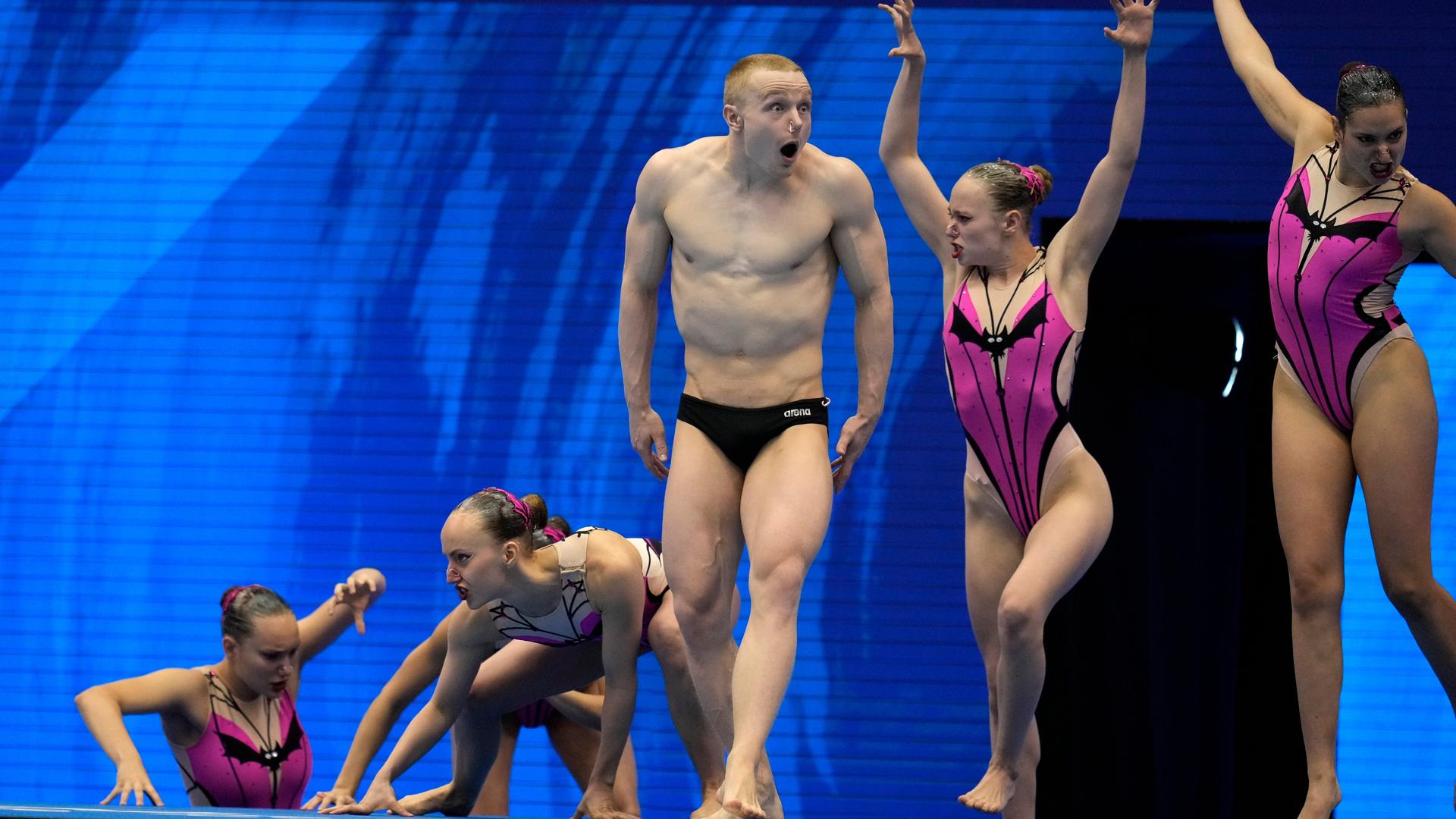 Das Foto zeigt vier Swimmerinnen und einen Schwimmer am Beckenrand. Sie nehmen an einem Wettbewerb in der Kategorie Akrobatik Routine teil.