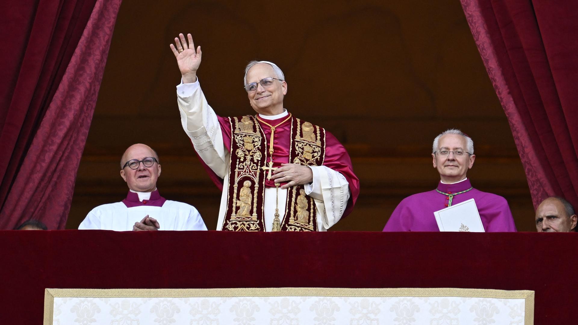Der neu gewählte Papst, Leo XIV, steht auf dem Balkon des Petersdoms im Vatikan am 8. Mai 2025. Seine Hände sind gefaltet und er hat ein Lächeln auf den Lippen - Er scheint sichtlich glücklich über sein neues Amt. 