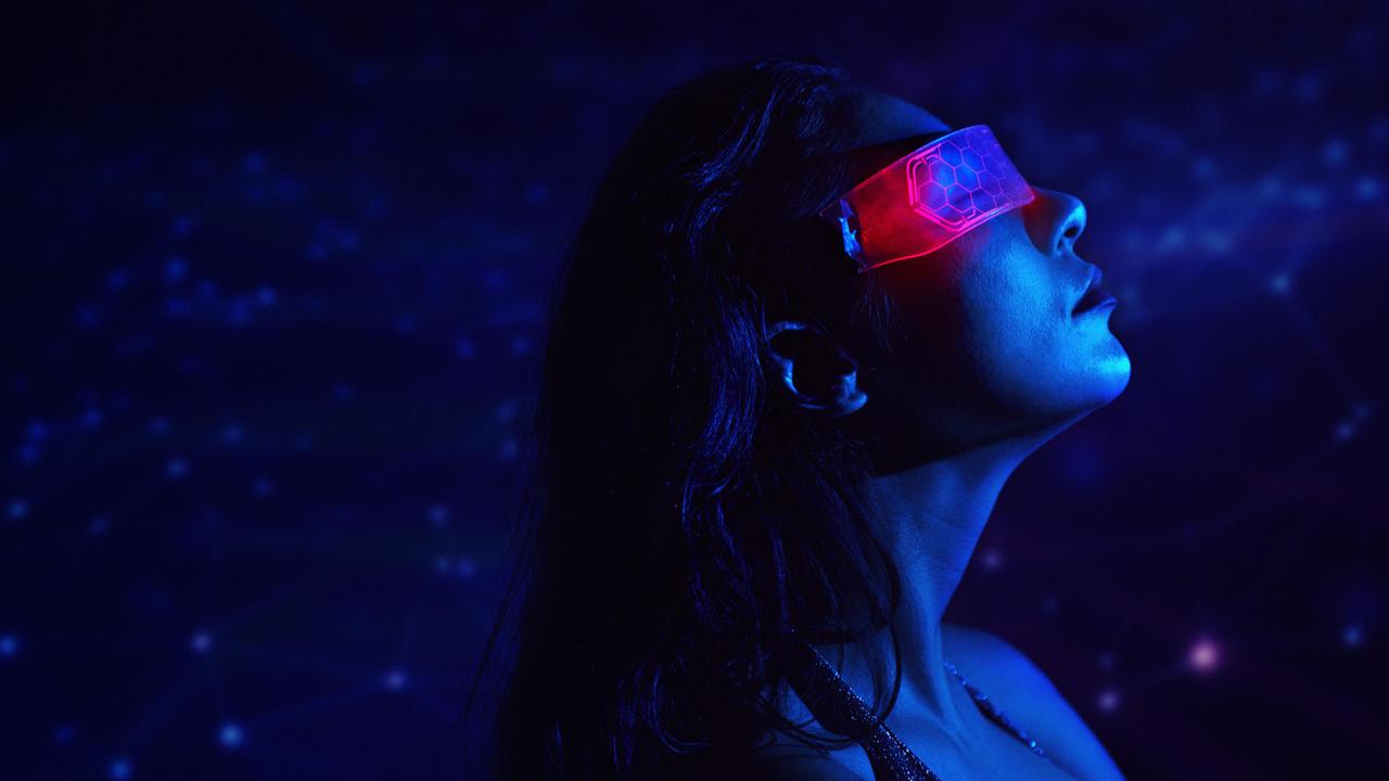 Eine Person trägt eine Neon-VR-Brille in einer futuristischen, blauen Cyberspace-Umgebung.
