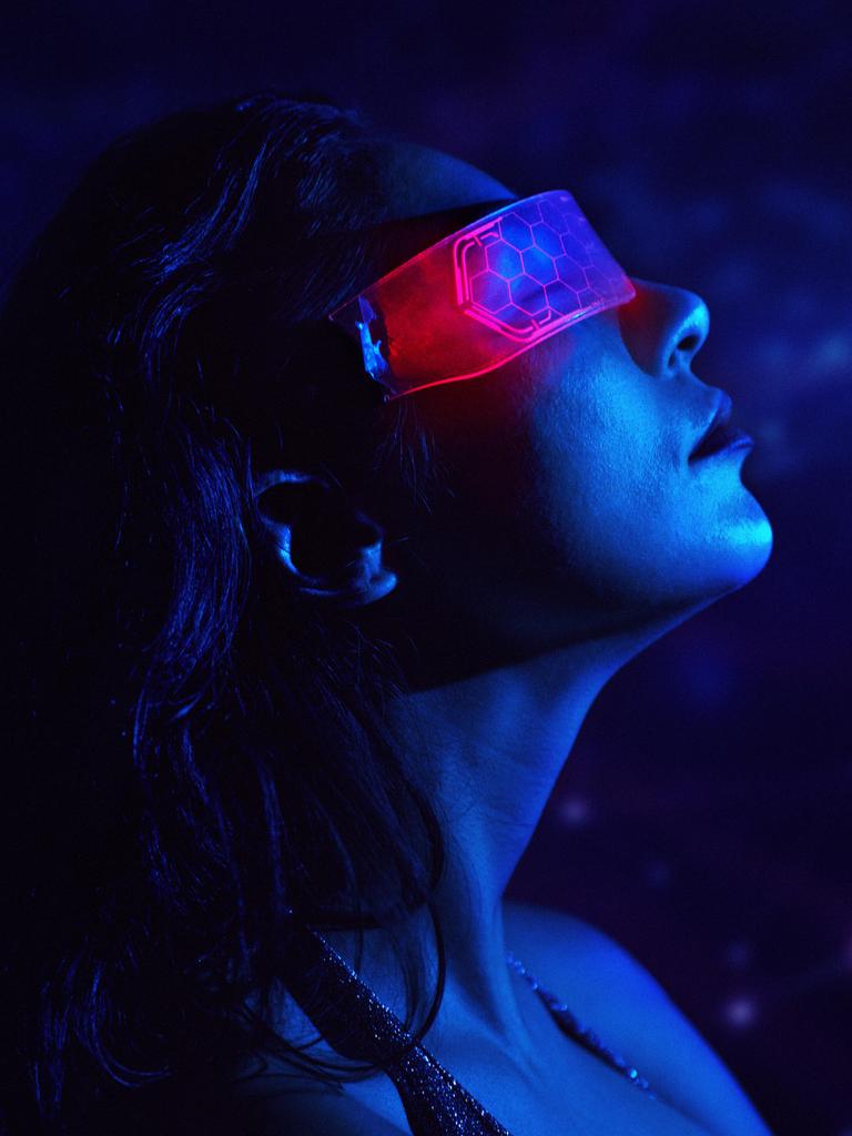 Eine Person trägt eine Neon-VR-Brille in einer futuristischen, blauen Cyberspace-Umgebung.
