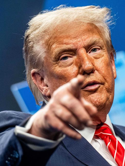 US-Präsident Trump steht an einem Rednerpult und zeigt mit seinem Finger nach vorne. 