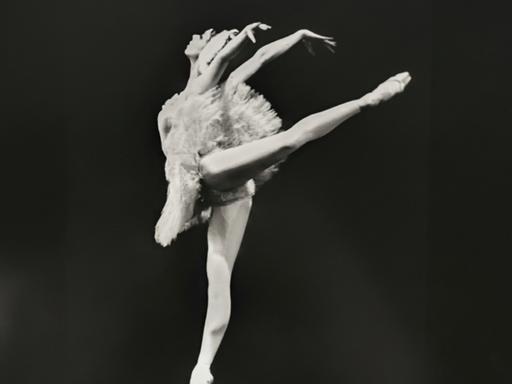 Schwarzweißfoto einer Ballerina im weißen Tanzkleid auf der Bühne.