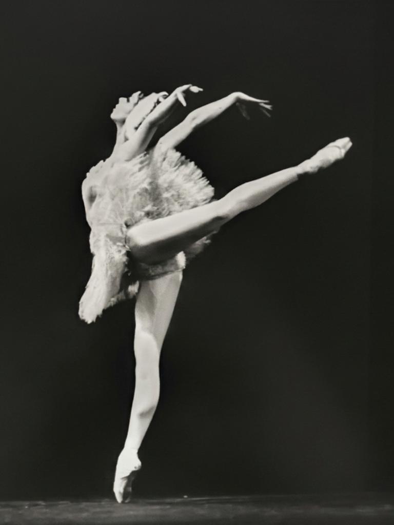 Schwarzweißfoto einer Ballerina im weißen Tanzkleid auf der Bühne.