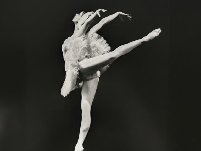 Schwarzweißfoto einer Ballerina im weißen Tanzkleid auf der Bühne.