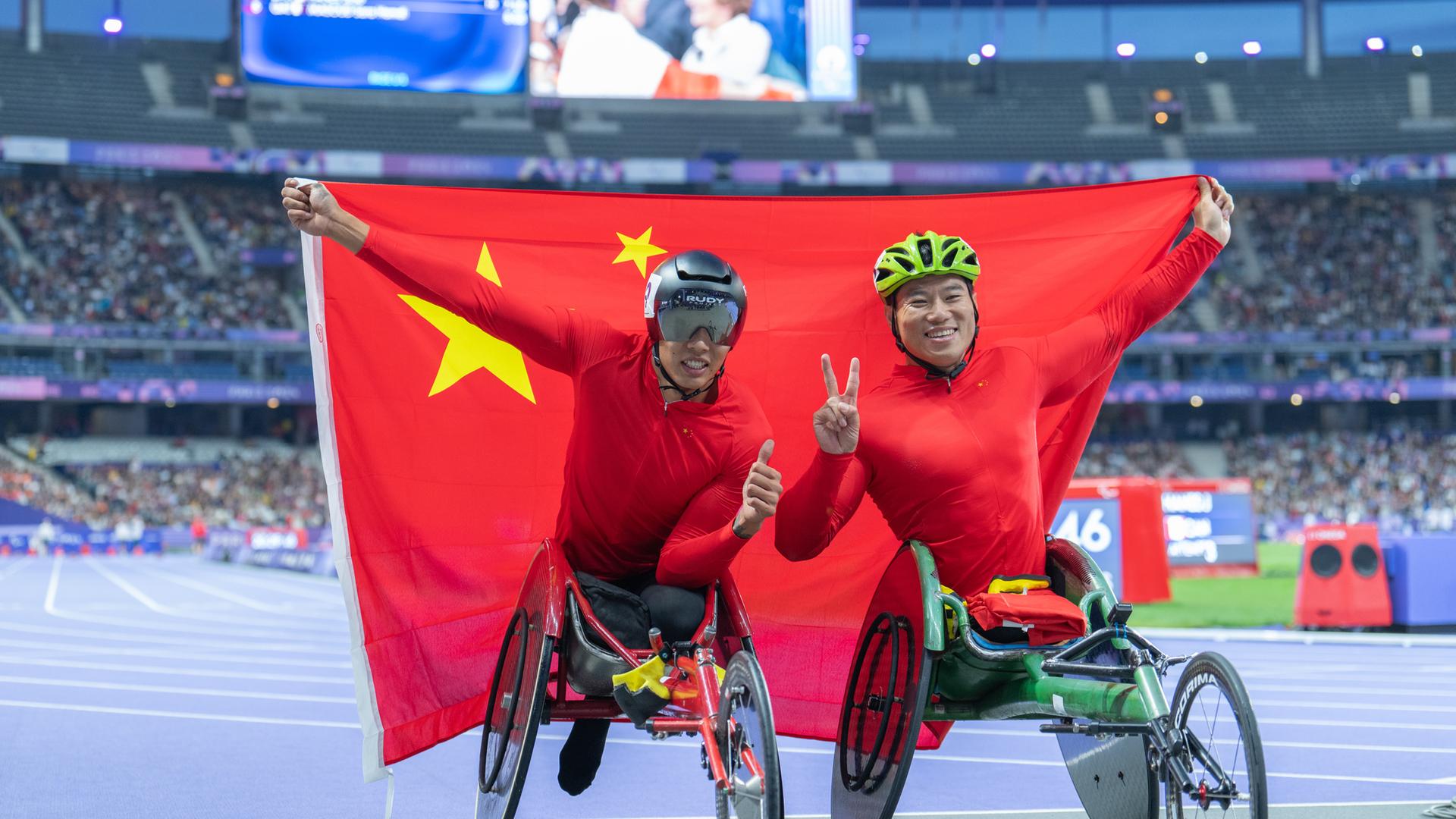 Jin Hua (links) und Dai Yunqiang aus China posieren nach dem 800-m-T54-Finale der Männer in der Para-Leichtathletik bei den Paralympischen Spielen 2024 in Paris